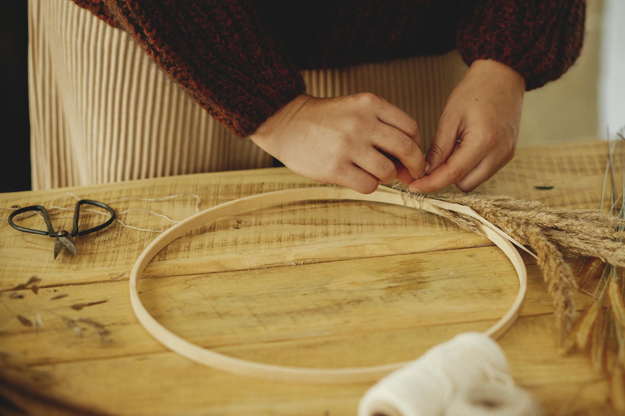 Artisan arranging threads and hoop in a sunlit studio